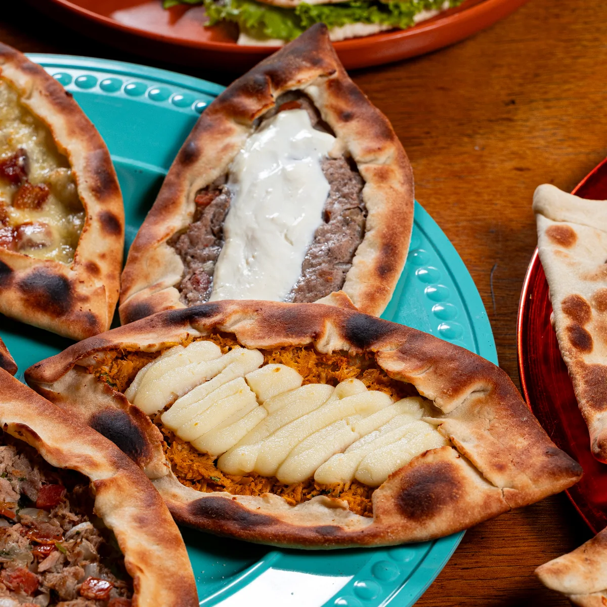 Esfihas abertas de carne, queijo e frango em pratos coloridos